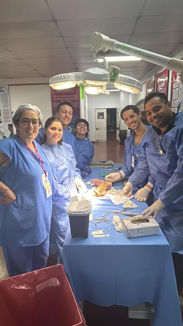 Grupo de participantes sonriendo junto a la mesa de trabajo con instrumental quirúrgico